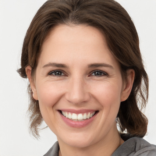 Joyful white young-adult female with medium  brown hair and grey eyes