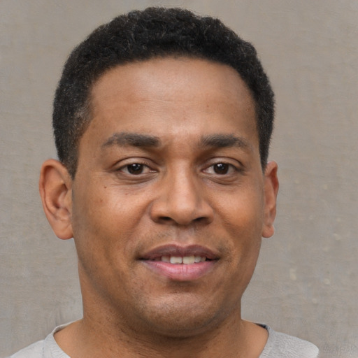 Joyful black young-adult male with short  brown hair and brown eyes