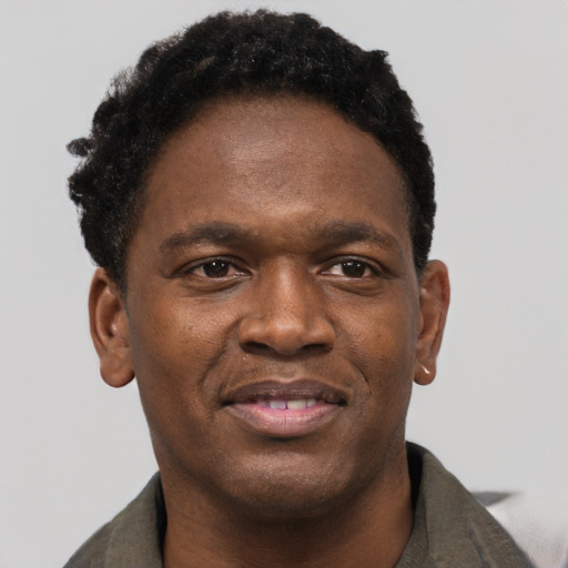 Joyful black young-adult male with short  brown hair and brown eyes