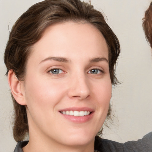 Joyful white young-adult female with medium  brown hair and grey eyes