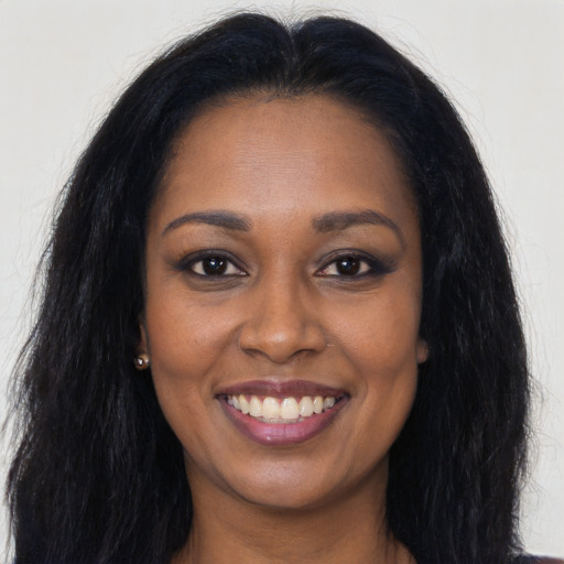 Joyful black young-adult female with long  brown hair and brown eyes