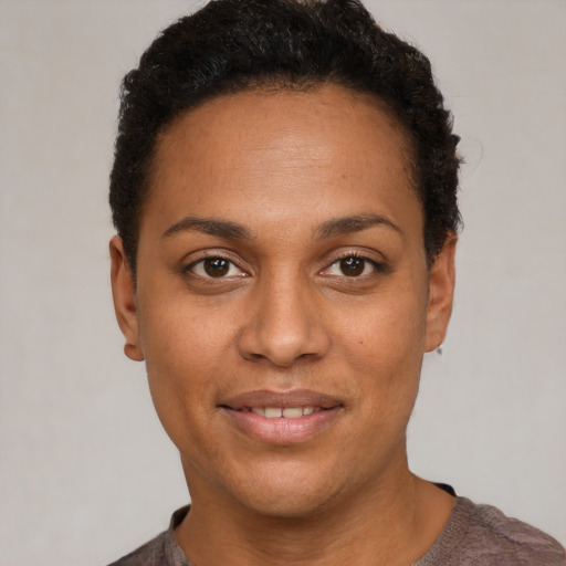 Joyful black young-adult female with short  black hair and brown eyes