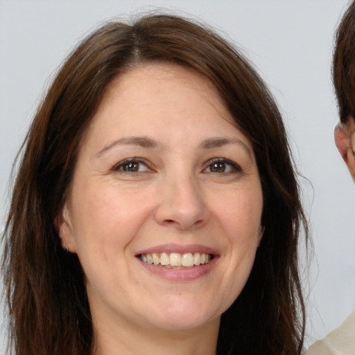 Joyful white adult female with long  brown hair and brown eyes