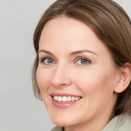 Joyful white adult female with medium  brown hair and blue eyes