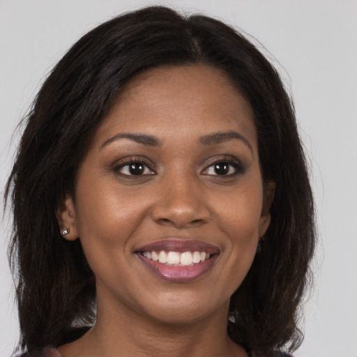 Joyful black young-adult female with long  brown hair and brown eyes