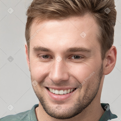 Joyful white young-adult male with short  brown hair and grey eyes