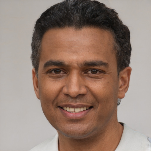 Joyful latino adult male with short  black hair and brown eyes
