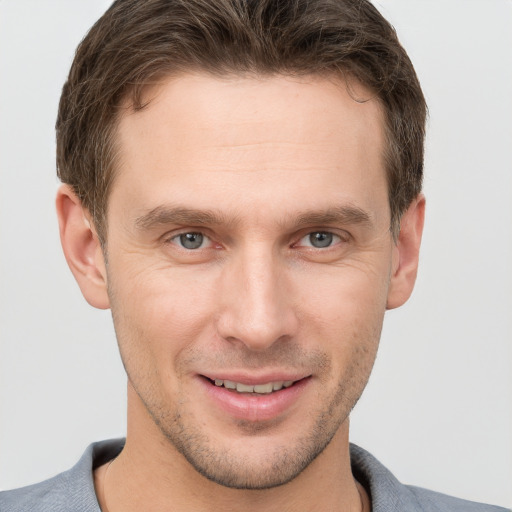 Joyful white young-adult male with short  brown hair and grey eyes