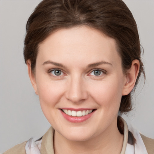 Joyful white young-adult female with medium  brown hair and grey eyes