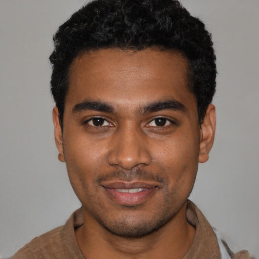 Joyful black young-adult male with short  black hair and brown eyes