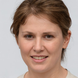 Joyful white young-adult female with medium  brown hair and grey eyes