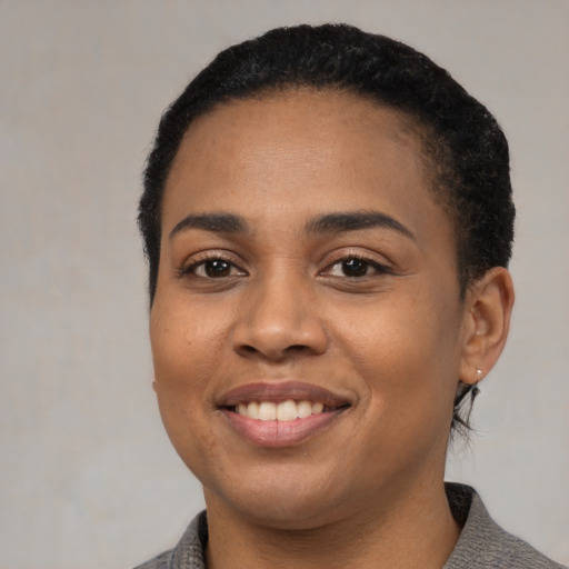 Joyful black young-adult female with short  black hair and brown eyes