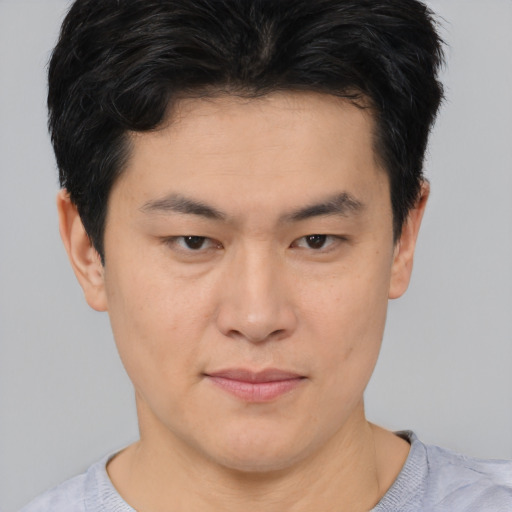 Joyful asian young-adult male with short  brown hair and brown eyes