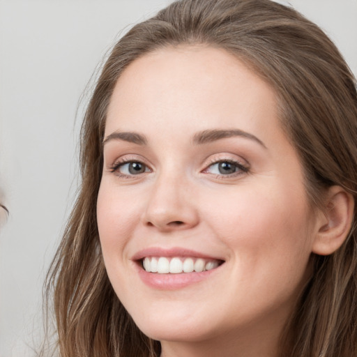 Joyful white young-adult female with long  brown hair and blue eyes