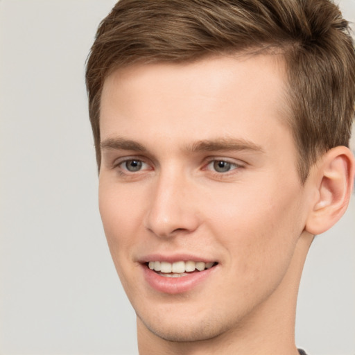 Joyful white young-adult male with short  brown hair and grey eyes