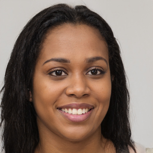 Joyful black young-adult female with long  brown hair and brown eyes