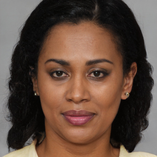 Joyful black adult female with long  brown hair and brown eyes