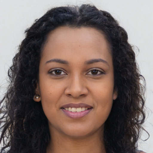 Joyful black young-adult female with long  brown hair and brown eyes