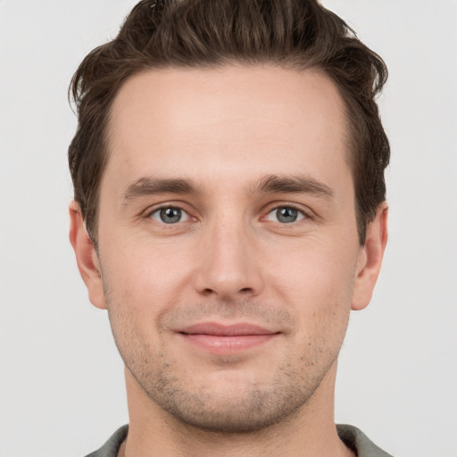 Joyful white young-adult male with short  brown hair and grey eyes