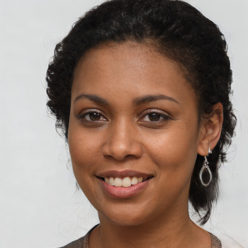 Joyful black young-adult female with long  black hair and brown eyes