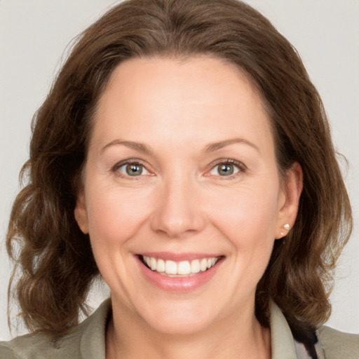 Joyful white adult female with medium  brown hair and green eyes