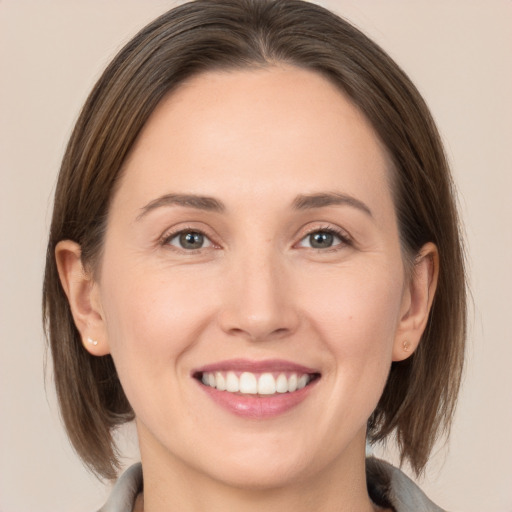 Joyful white young-adult female with medium  brown hair and grey eyes