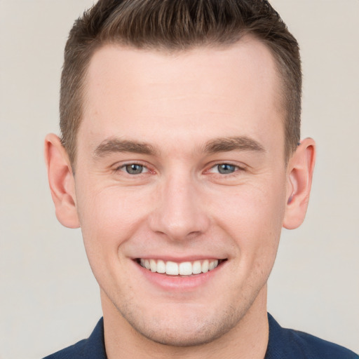 Joyful white young-adult male with short  brown hair and grey eyes