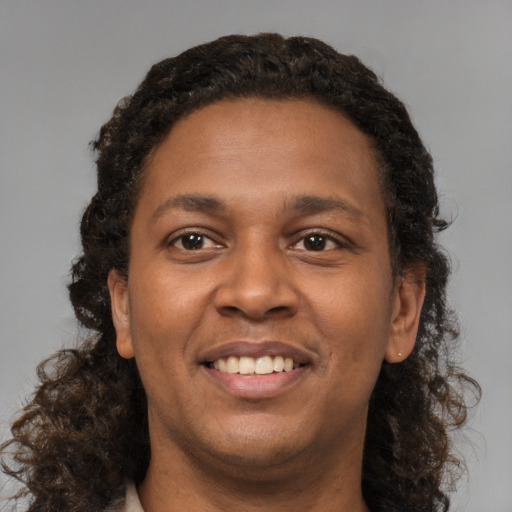 Joyful black young-adult female with long  brown hair and brown eyes