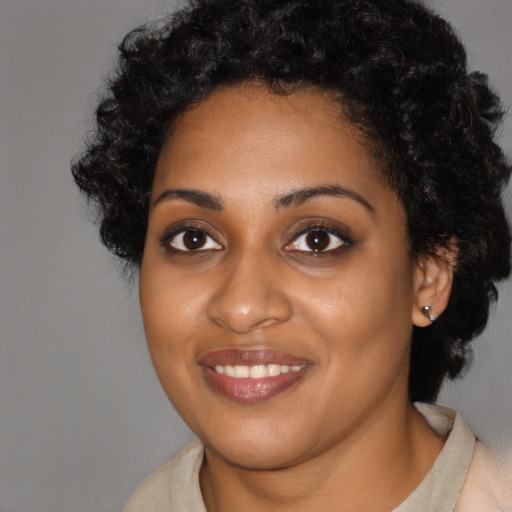 Joyful black young-adult female with short  black hair and brown eyes