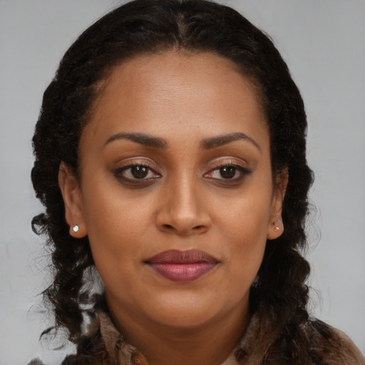 Joyful black young-adult female with long  brown hair and brown eyes