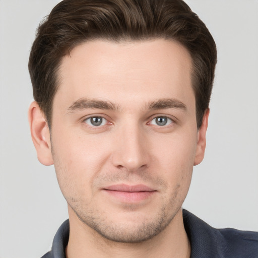 Joyful white young-adult male with short  brown hair and grey eyes