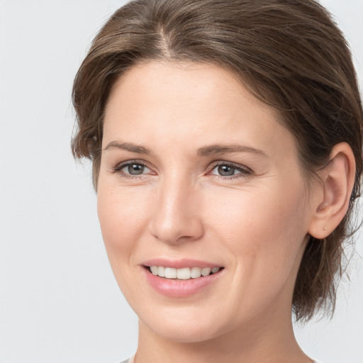 Joyful white young-adult female with medium  brown hair and grey eyes