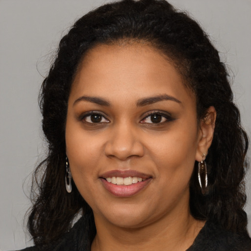 Joyful black young-adult female with long  brown hair and brown eyes