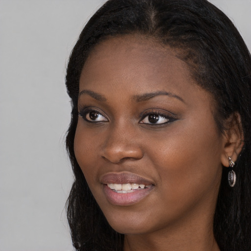 Joyful black young-adult female with long  brown hair and brown eyes