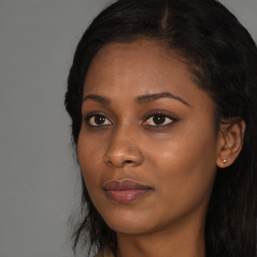 Joyful black young-adult female with long  black hair and brown eyes