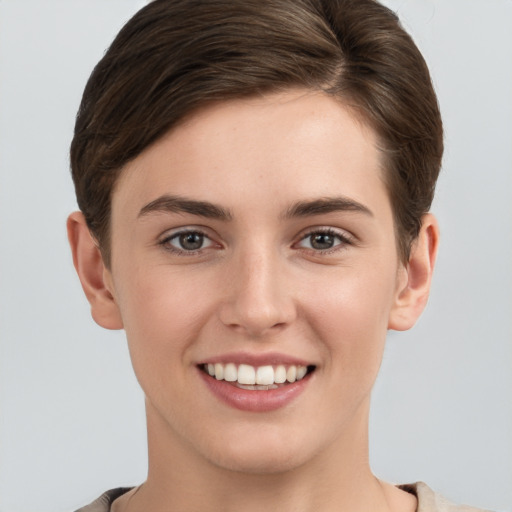 Joyful white young-adult female with short  brown hair and grey eyes