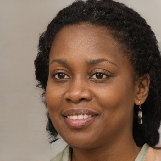 Joyful black young-adult female with long  black hair and brown eyes