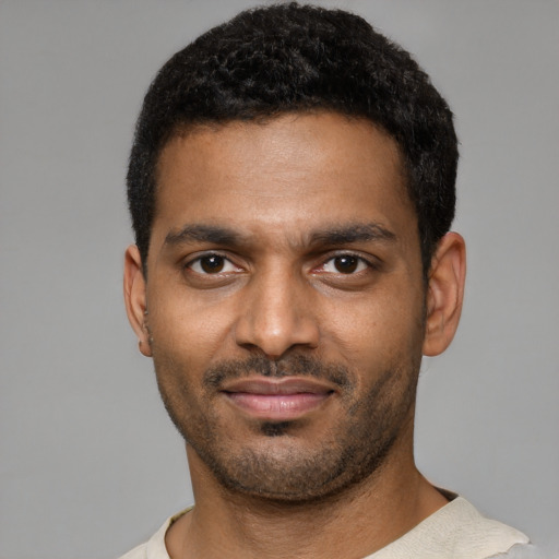 Joyful black young-adult male with short  black hair and brown eyes