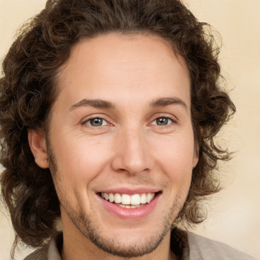 Joyful white young-adult male with long  brown hair and green eyes