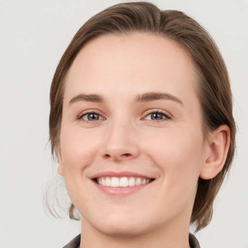 Joyful white young-adult female with medium  brown hair and grey eyes