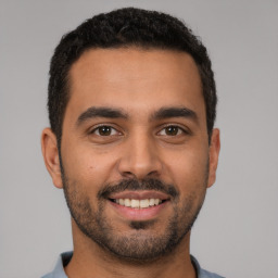 Joyful latino young-adult male with short  black hair and brown eyes