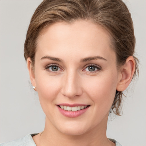 Joyful white young-adult female with medium  brown hair and grey eyes