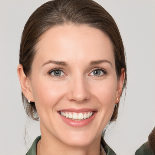 Joyful white young-adult female with medium  brown hair and grey eyes