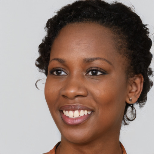Joyful black young-adult female with long  brown hair and brown eyes