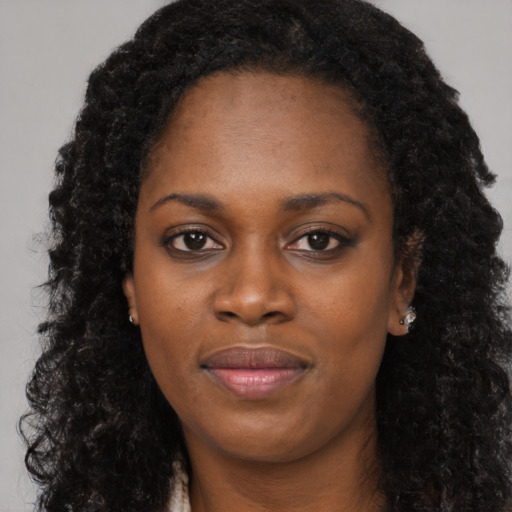 Joyful black young-adult female with long  black hair and brown eyes