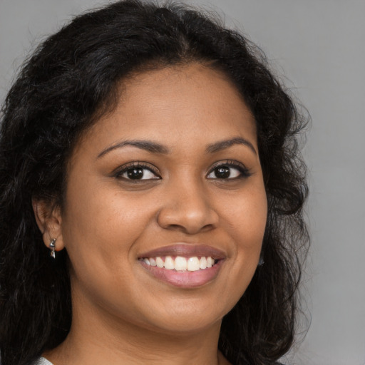 Joyful black young-adult female with long  brown hair and brown eyes