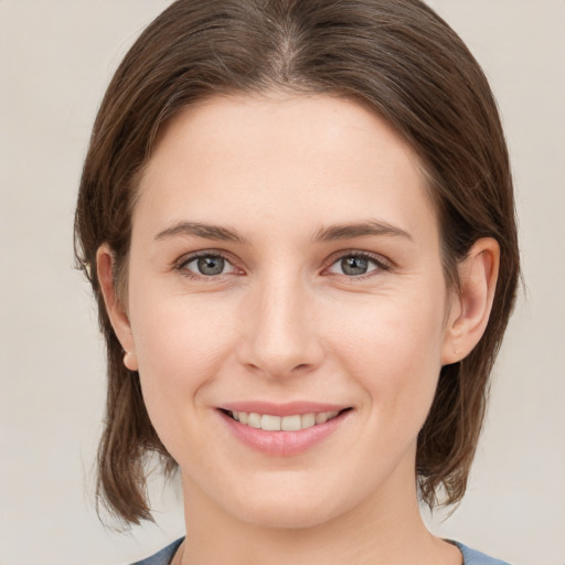 Joyful white young-adult female with medium  brown hair and grey eyes