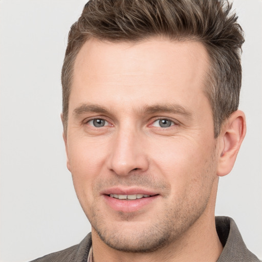 Joyful white young-adult male with short  brown hair and grey eyes