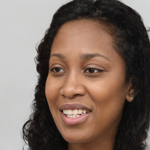 Joyful black young-adult female with long  black hair and brown eyes