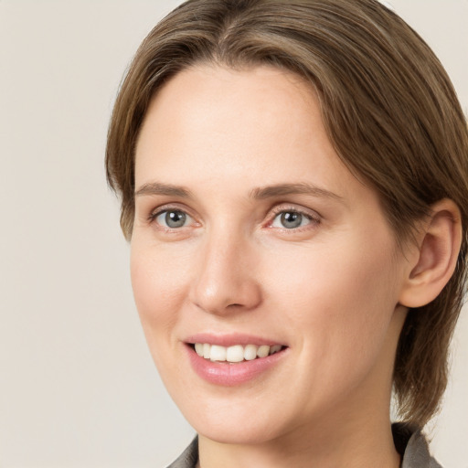 Joyful white young-adult female with medium  brown hair and grey eyes